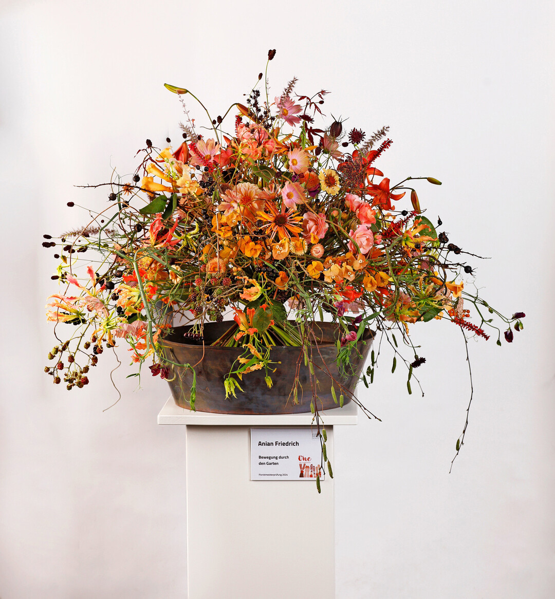 <b>Anian Friedrich</b>
 kombinierte eine Vielzahl von Blten und Frchten und nannte seinen Strau Bewegung durch den Garten. Das Farbspektrum reicht von hellen Pastelltnen bis Schwarz. Ob Schwarz, Gelb, Rosa oder Orange, alle Farben sind in verschiedenen Floralien vertreten. Blten mit Farbverlufen sorgen fr weiche bergnge und einen harmonischen Gesamteindruck.