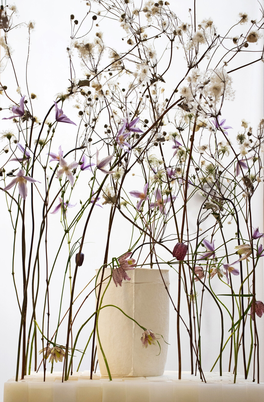 Die Farben der Clematis-Blten an der Grenze zwischen Leuchten und Verblassen gepaart mit den weichen Fruchtstnden der Herbst-Hnemone geben der handgeschpften Papierurne aus Hanffasern von Kristina Rothe ein geborgenes Umfeld.
