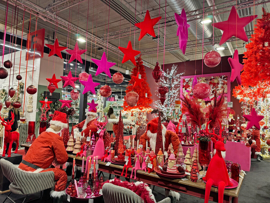 Am Stand der Firma AM Design sind die Farben Pink und Rot der Eyecatcher. Der Tischaufbau mit den Weihnachtsmännern lässt sich einfach umsetzen und mit roten Weihnachtssternen ergänzen. Wer keine Schaufensterfiguren hat, kann die Weihnachtsmannanzüge mit Holzwolle ausstopfen und den Kopf aus beigefarbenem Stoff (auch mit Holzwolle gefüllt) mit einem Bart und einer roten Nase und der Nikolausmütze „über den Augen“ nachbilden. Diese Inszenierung würde auch als traditioneller Aufbau in Rot/Grün wirken. Der Tisch dient als Inspiration für die Besucher des Gartencenters. Die Ware zum Kauf sollte in der Nähe zur Verfügung stehen.