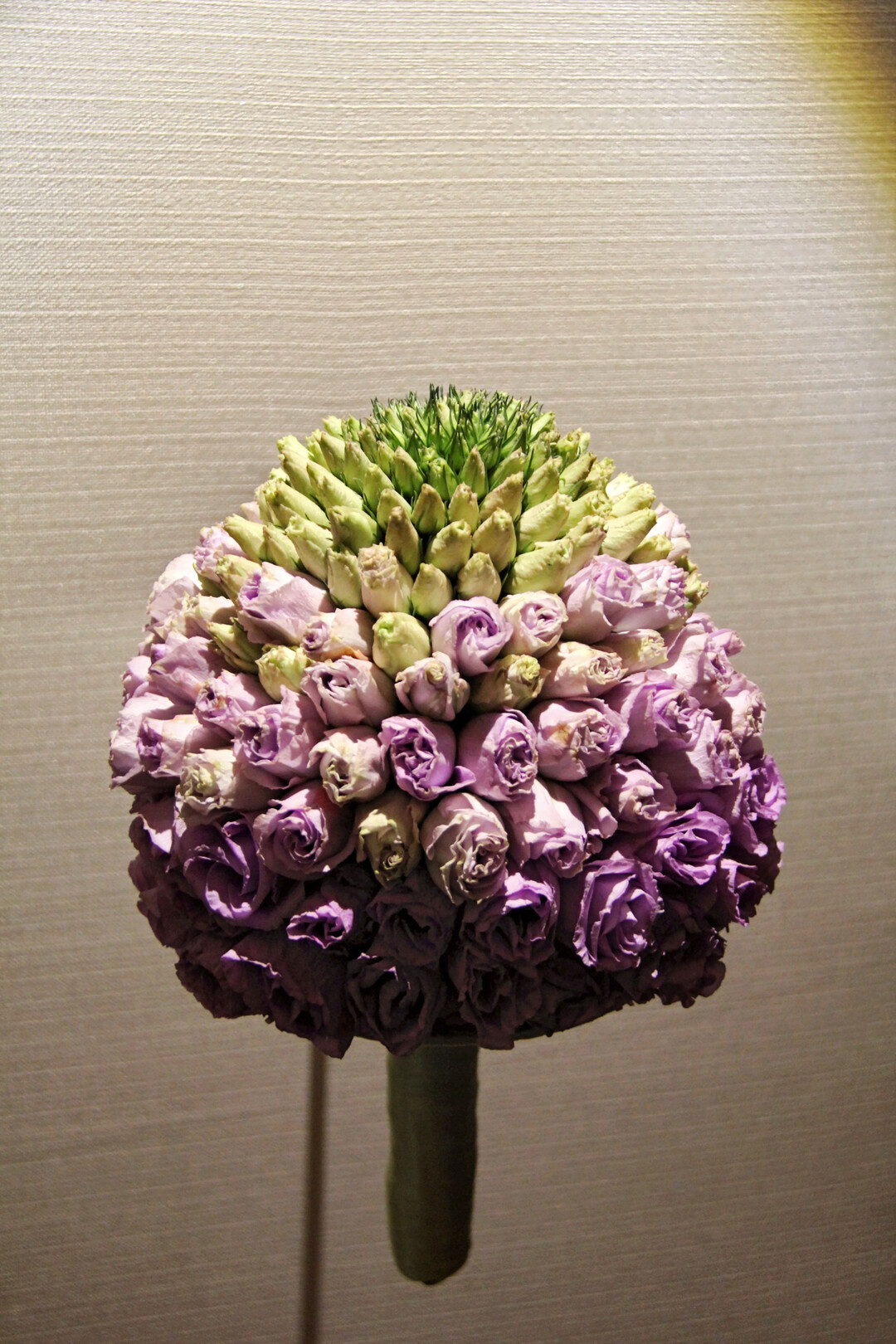 <b>Barbara Schildendorfer</b>
gestaltete einen englischen Brautstrauß aus
<i>Lisianthus</i>
-Blüten. Jede einzelne Knospe und Blüte wurde gedrahtet und dann auf eine Mittelrippe getapt. Dies ist eine eigene Technik, die nur beim englischen Brautstrauß angewendet wird. Alle pflanzlichen Materialien müssen dazu sehr gut vorgewässert sein. Den kleinen Blütenknospen folgen größere, farbigere. So entstand eine märchenhafte Kuppel, die durch eine seidige, zarte Textur verzauberte.