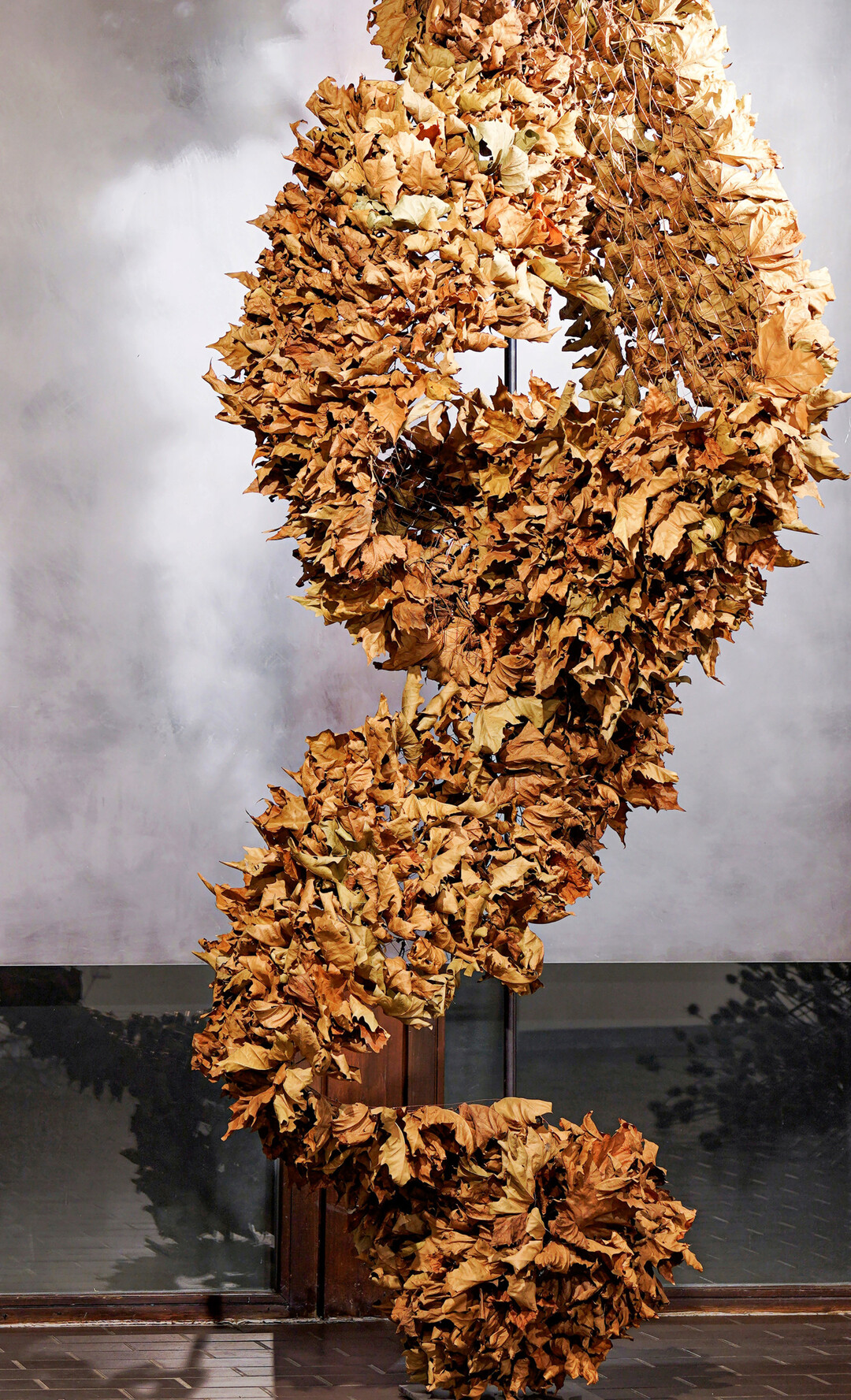 Wie eine schtzende, wrmende Decke hllen die Platanenbltter eine imaginre Figur ein. Durch die Anordnung entsteht in der Mitte eine Art Kokon oder Hhle mit beschtzendem Charakter, genau wie ein Laubhaufen im Garten, der Schutz fr Igel und andere kleine Tiere bietet.