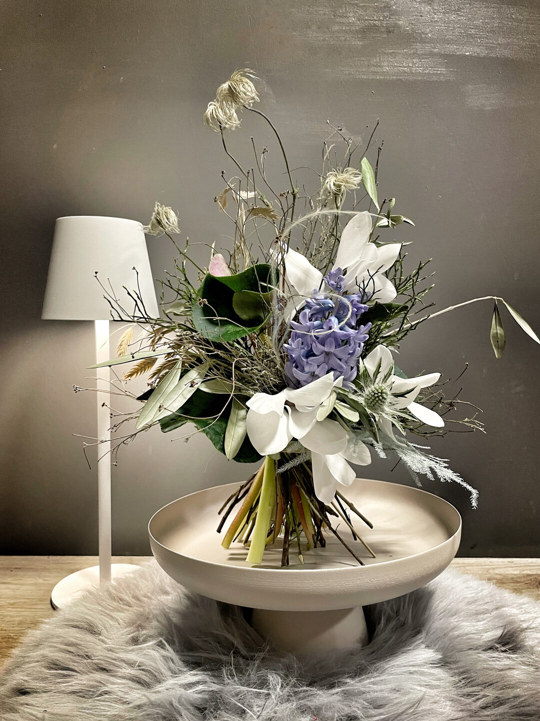 Dominique Wienholt, Eventfloristik Wienholt (
<a href="https://www.instagram.com/eventfloristik_wienholt/"  target="_blank" >@eventfloristik_wienholt</a>
) in Alzey setzte ihren Strau mit winterlichem Acessoires in Szene. Dominique Wienholt, Eventfloristik Wienholt in Alzey, gestaltet ihren Laden in den ersten Wochen des Ladens bewusst zurckhaltend-winterlich. Aktuell habe ich mit Fell und alten Ski dekoriert und alles, was so in die Richtung Schnee und Vergnglichkeit sowie Neuanfang geht, erzhlt die Floristin. 