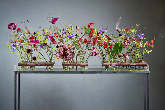 Like the �She blooms� initiative, Elisabeth Schoenemann�s piece consists of three parts that support one another, thereby combining their dynamic energy. As an alternative to floral wire, the florist has drilled multiple holes through heavy clinker bricks. 