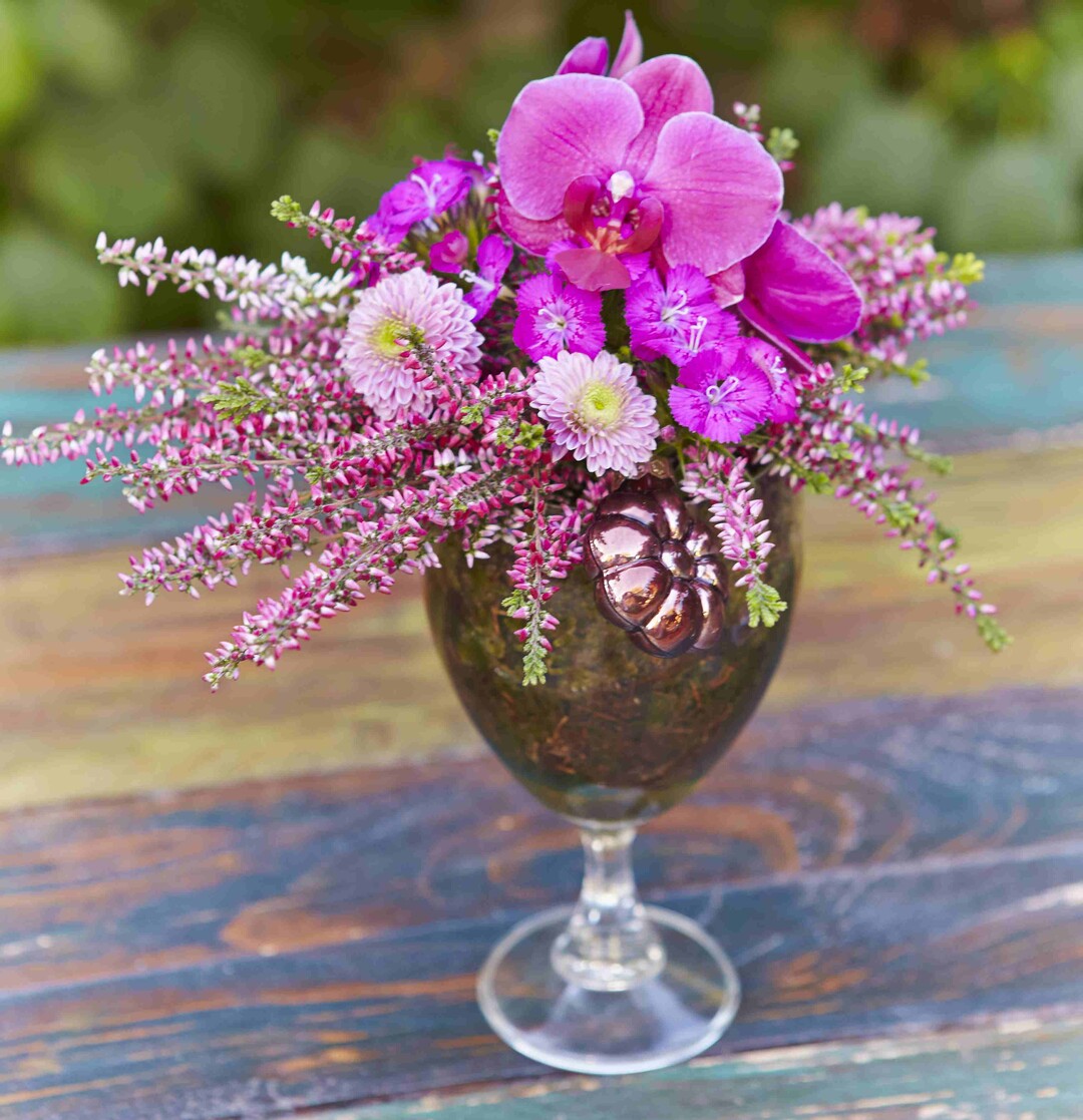 Das Gesteck aus Knospenheide, Chrysanthemen, Nelken und einer Orchideenblte strahlt frhlichen Optimismus aus.