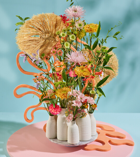 „Beach Club“ nennt das FDF-Trendteam dieses Straußdesign im Sommer-Trend „Soft Shore“. Folgende Floralien wurden verwendet:
<i>Kniphofia</i>
,
<i>Lisianthus</i>
, Carnation,
<i>Echeveria</i>
, Jatropha, Spray Carnation,
<i>Lathyrus</i>
,
<i>Celosia, Nerine, Cosmea, Phlox.</i>